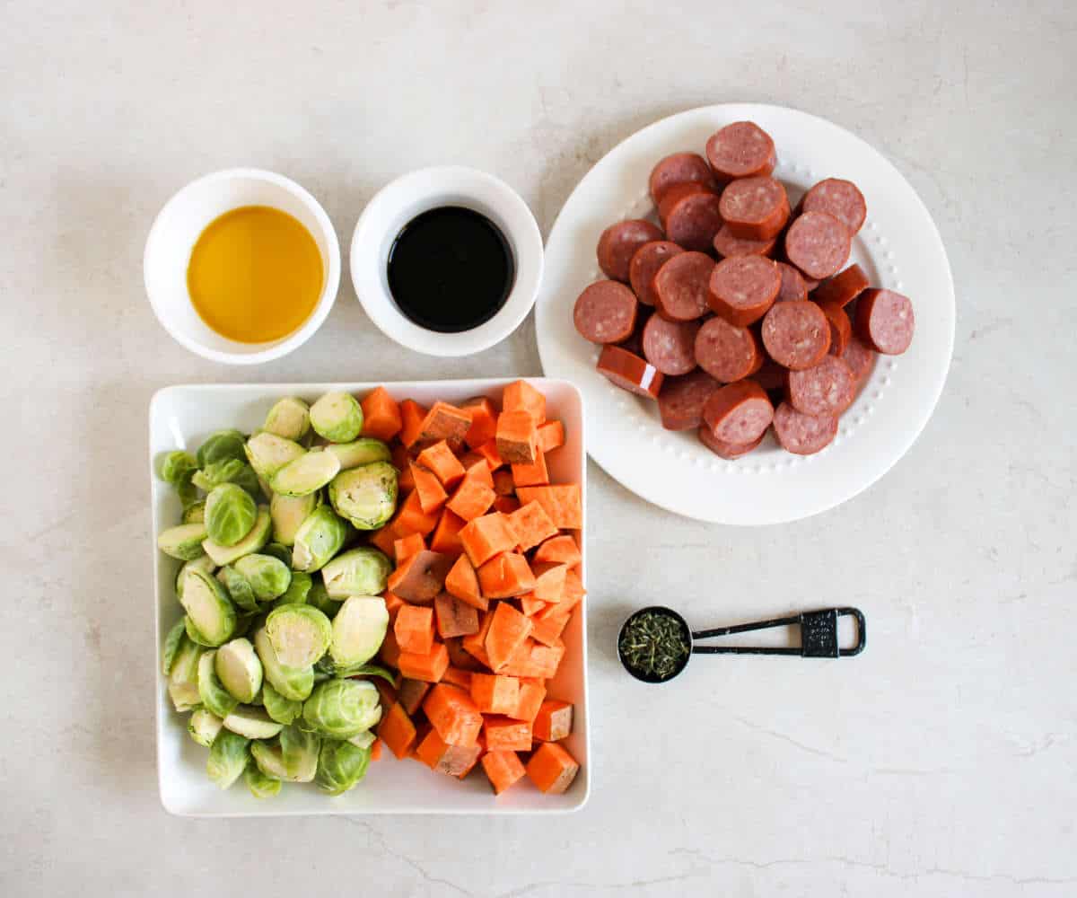 sausages, onion, yukon gold potatoes, sweet mini peppers, garlic salt, seasonings, oil, and balsamic vinegar on white marble counter.