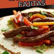 Two Chili's steak fajitas with onions and red peppers on a blue plate, lime slice and garnish.