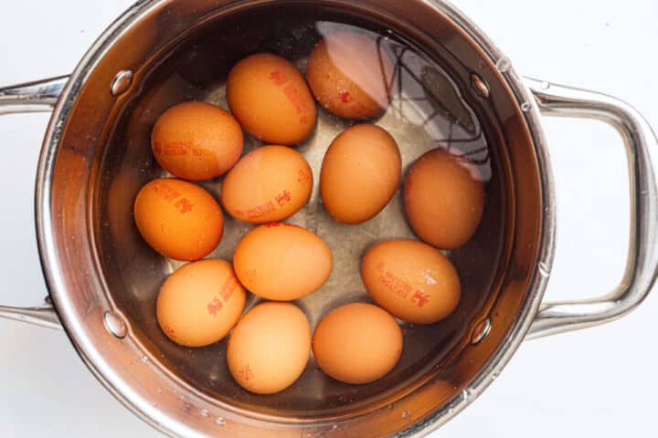 Eggs boiling in a stainless steel pot with water for cooking.