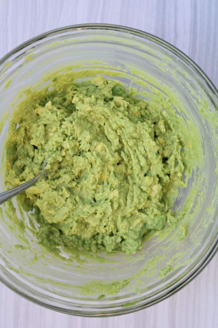 Mashed avocado in a bowl for a simple guacamole recipe.