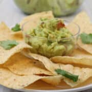 Guacamole with tortilla chips on a platter.