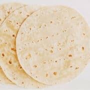 Stack of homemade flour tortilla on napkin.