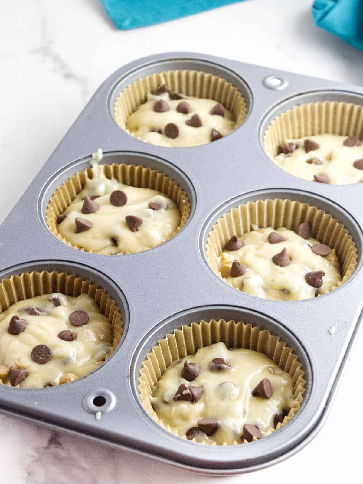 muffin tin filled with paper liners and batter.