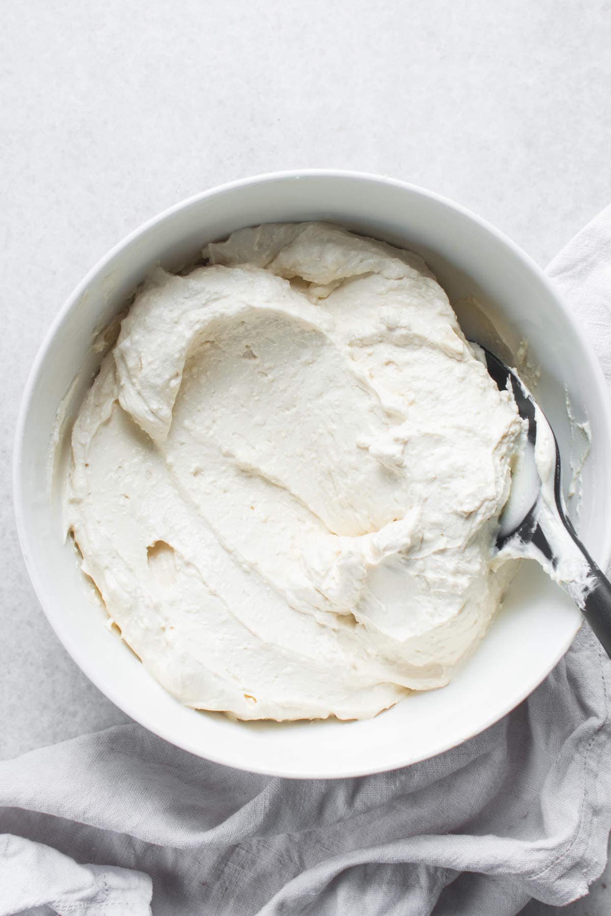 Spoon lifting thick homemade Greek yogurt.
