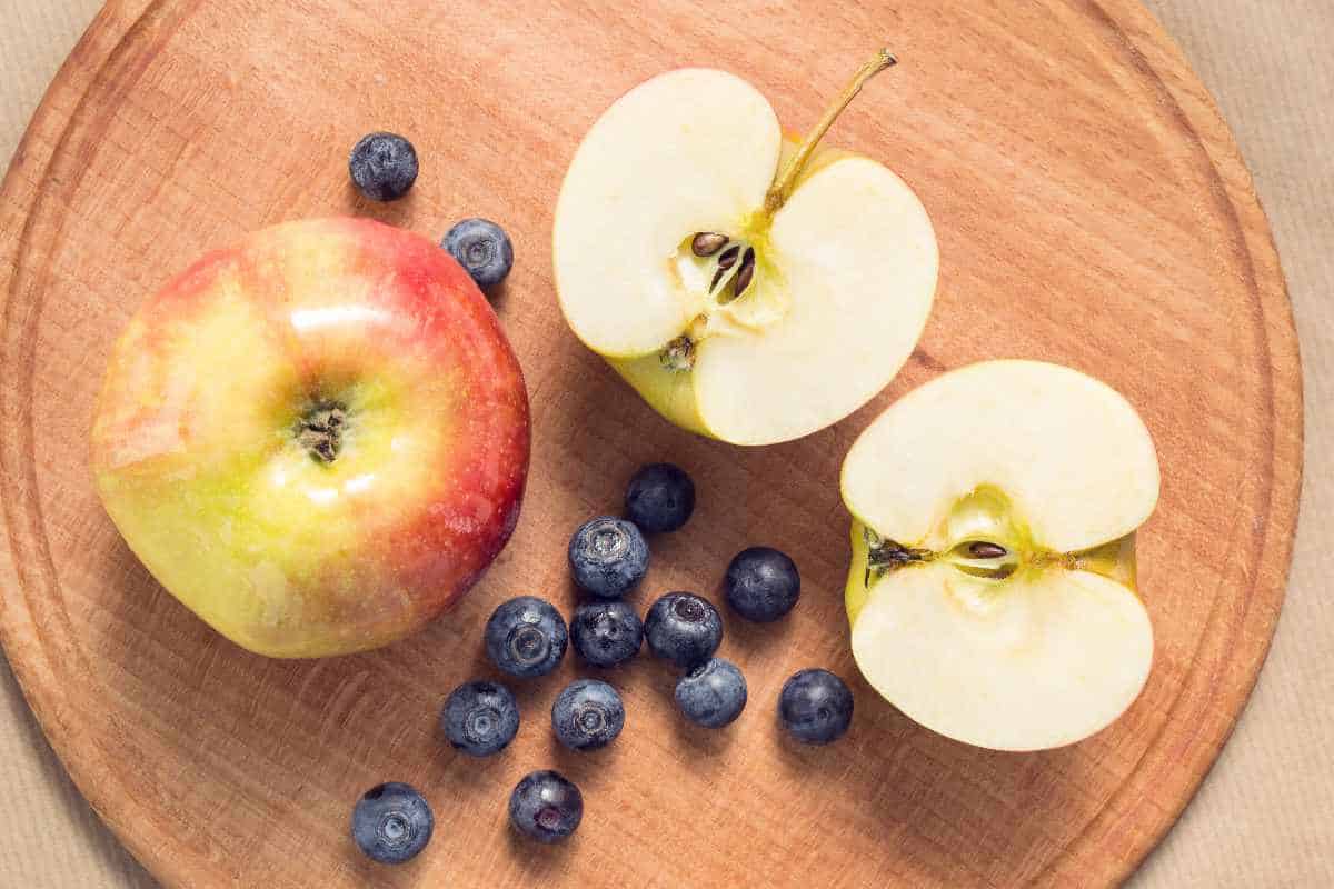 cutting board with apples and blueberries.