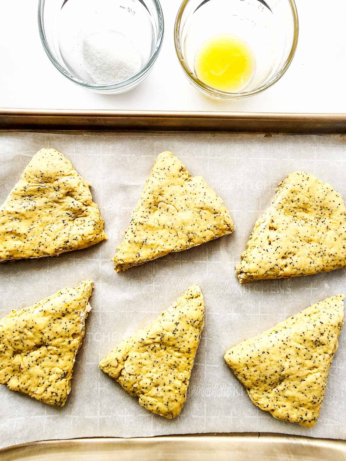 poppy seed scones on a parchment covered baking sheet.