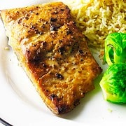 Salmon filet in a serving dish with rice pilaf and brussels sprouts.