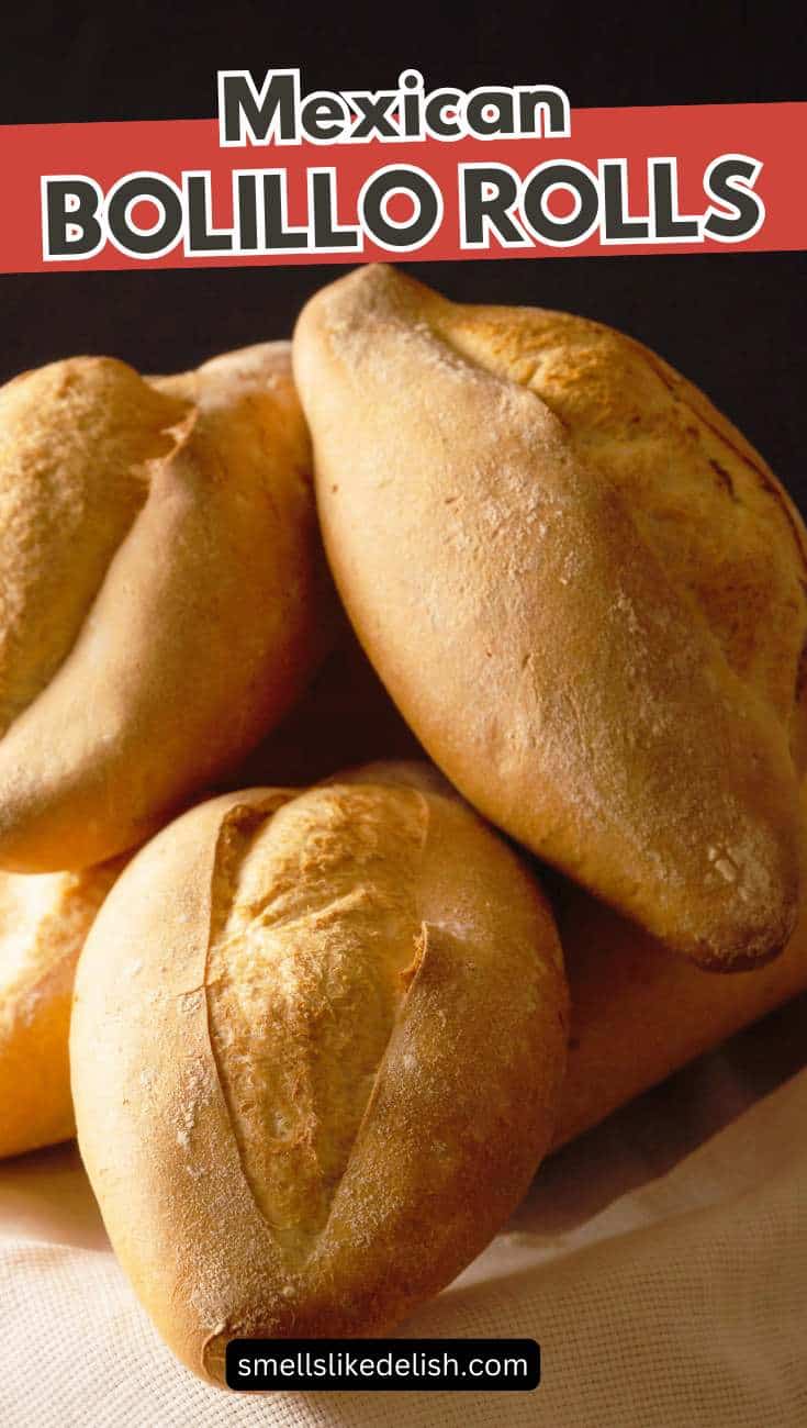 A close-up of several golden-brown Mexican bolillo rolls stacked together on a cloth, with a red banner at the top reading "Mexican Bolillos.