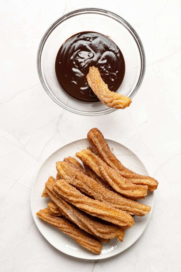 Dipping cinnamon sugar churro into chocolate sauce.