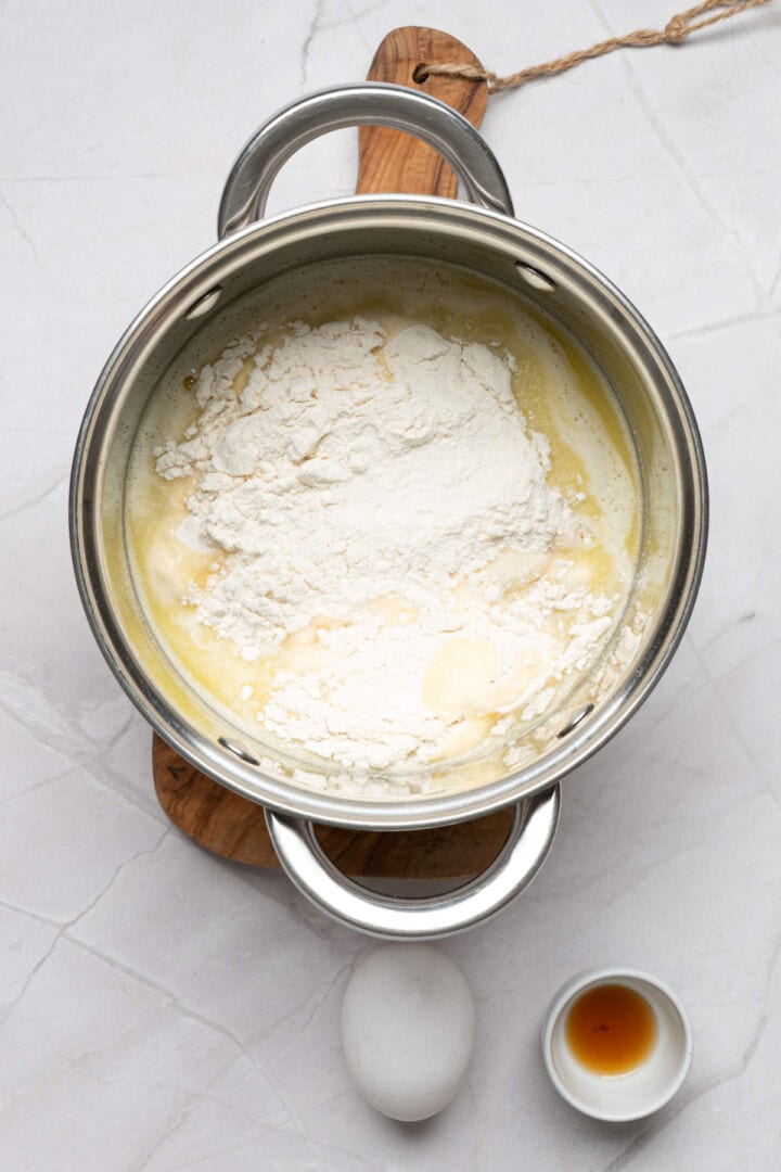 Adding flour to hot liquid mixture to form churro dough.