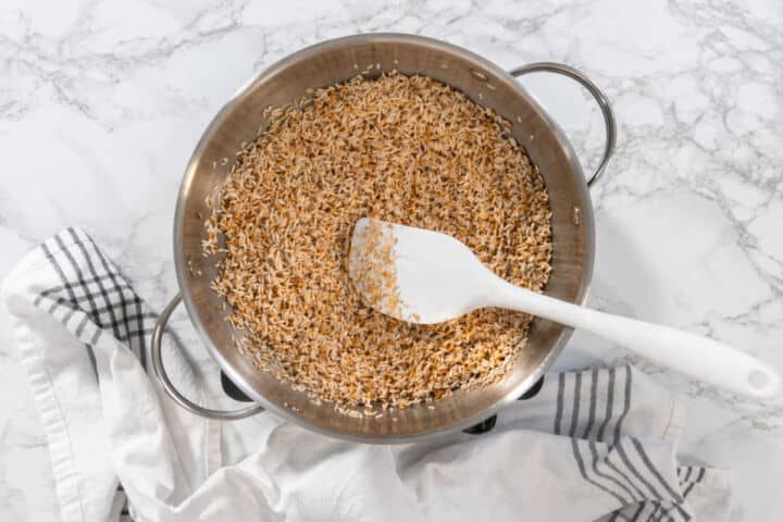 Rice toasting in oil in a wide skillet with a spatula until lightly golden.