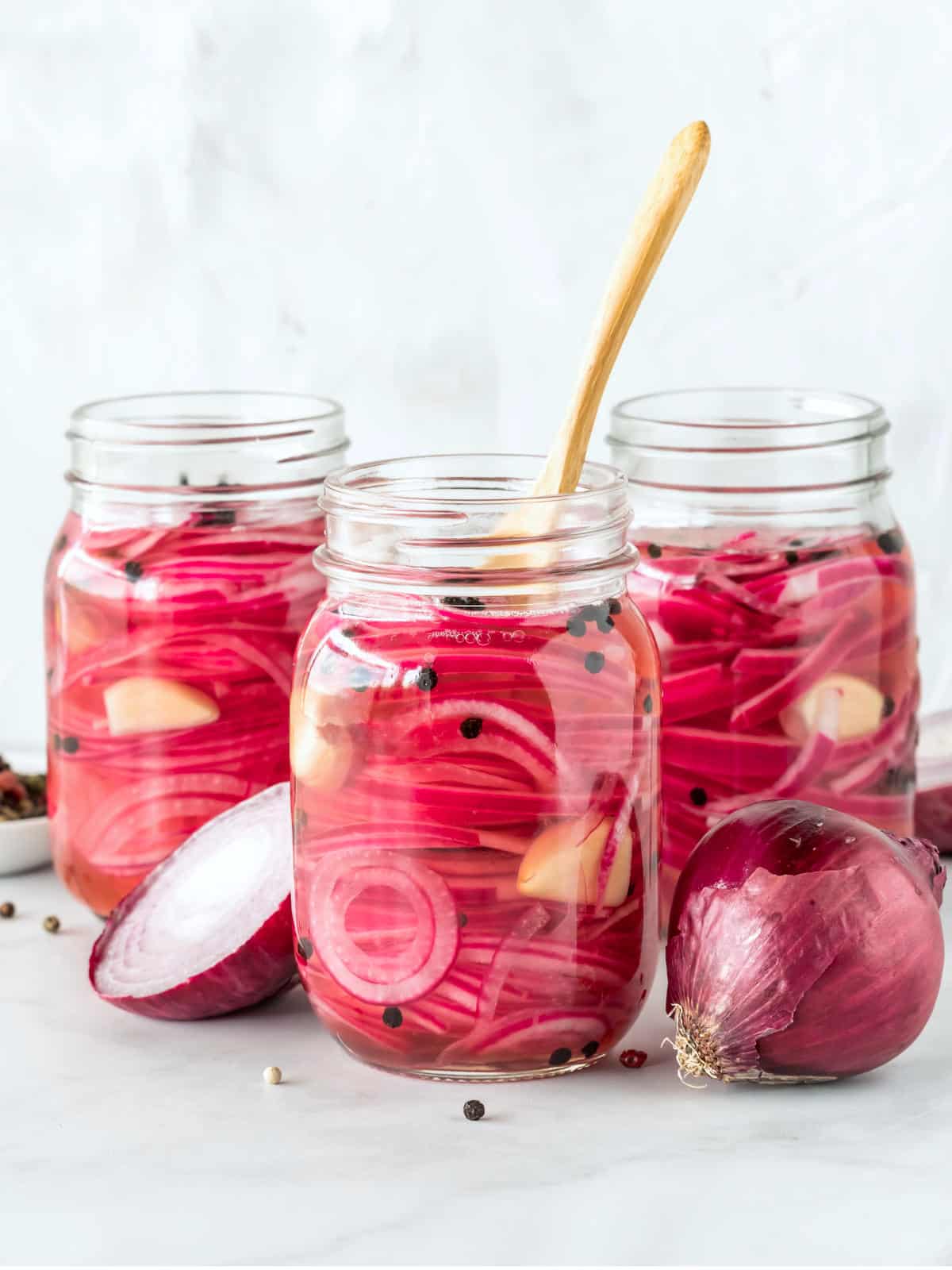 Jar of Mexican pickled red onions on a light background.