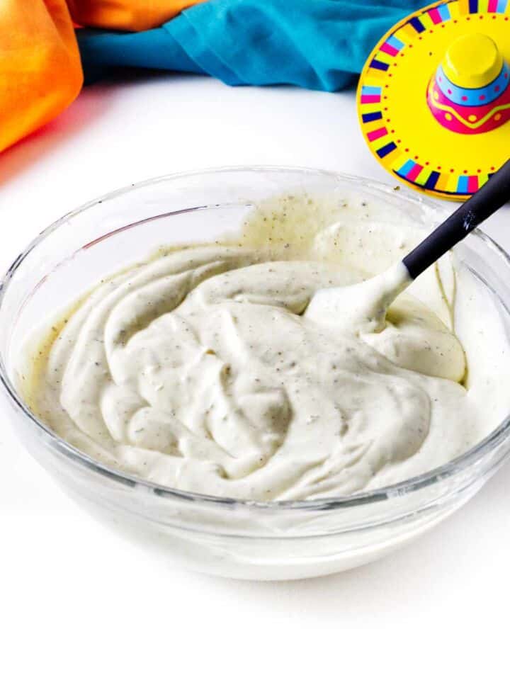 Creamy Mexican white sauce fully mixed with visible herbs and smooth texture.