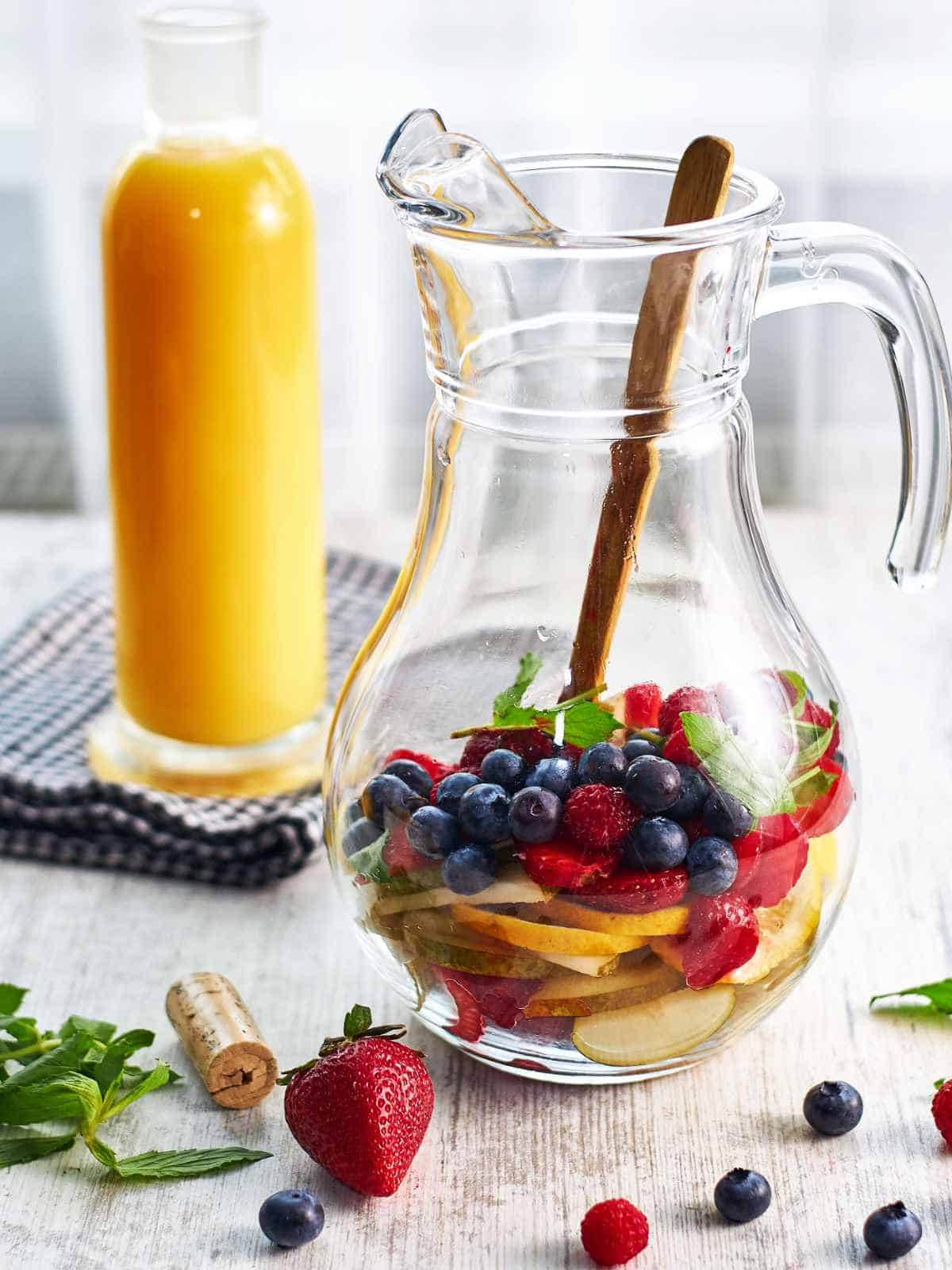 pitcher of blueberries, strawberries, sparkling wine and orange juice.