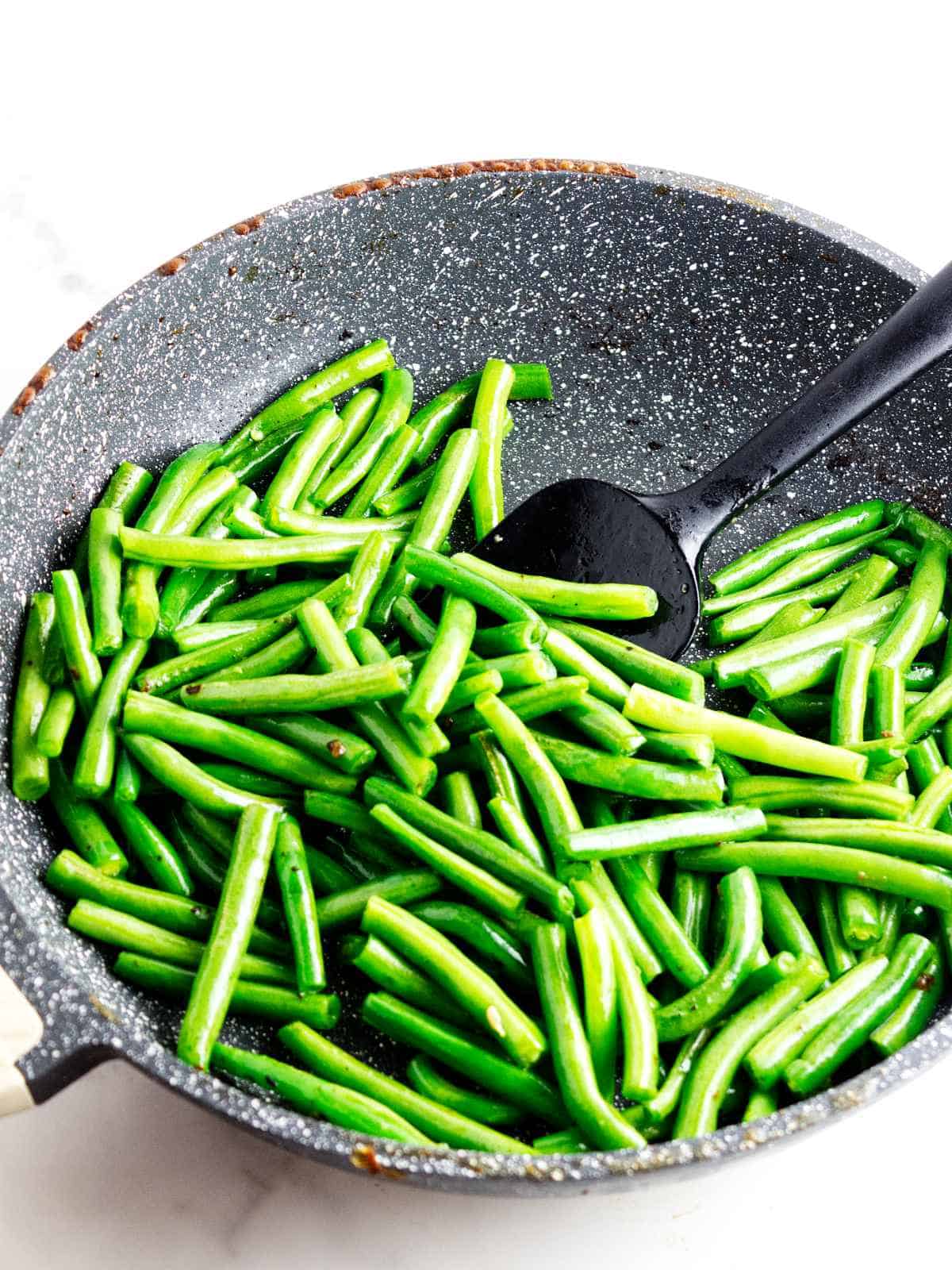 Fresh green beans stir frying in a skillet for Panda Express String Bean Chicken.