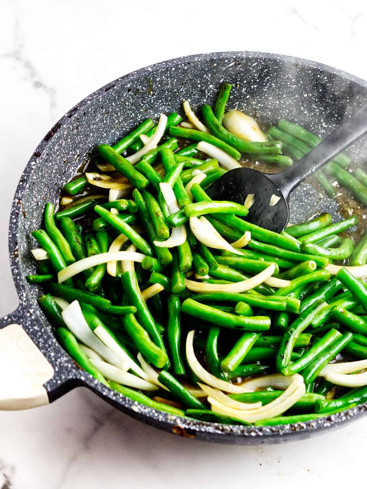 Green beans and onions cooking in ginger soy sauce for Panda Express String Bean Chicken copycat.