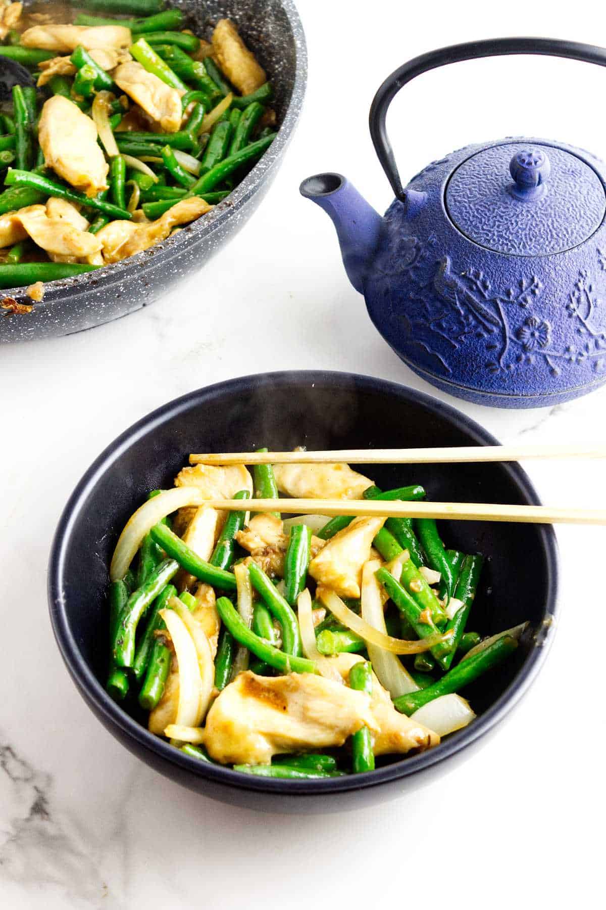 Bowl of Panda Express String Bean Chicken copycat with chicken, green beans, onions, and ginger soy sauce.