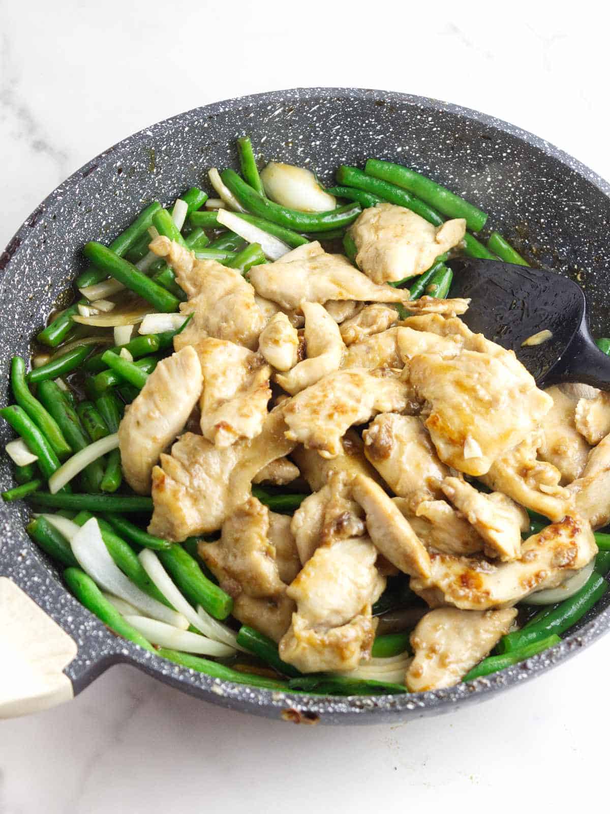 sauteed chicken added to skillet of sauteed green beans.