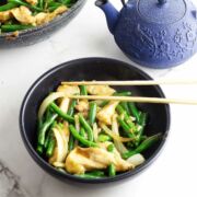 serving bowl of panda express string bean chicken with blue teapot nearby.