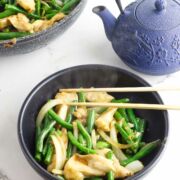 serving bowl of panda express string bean chicken with blue teapot nearby.