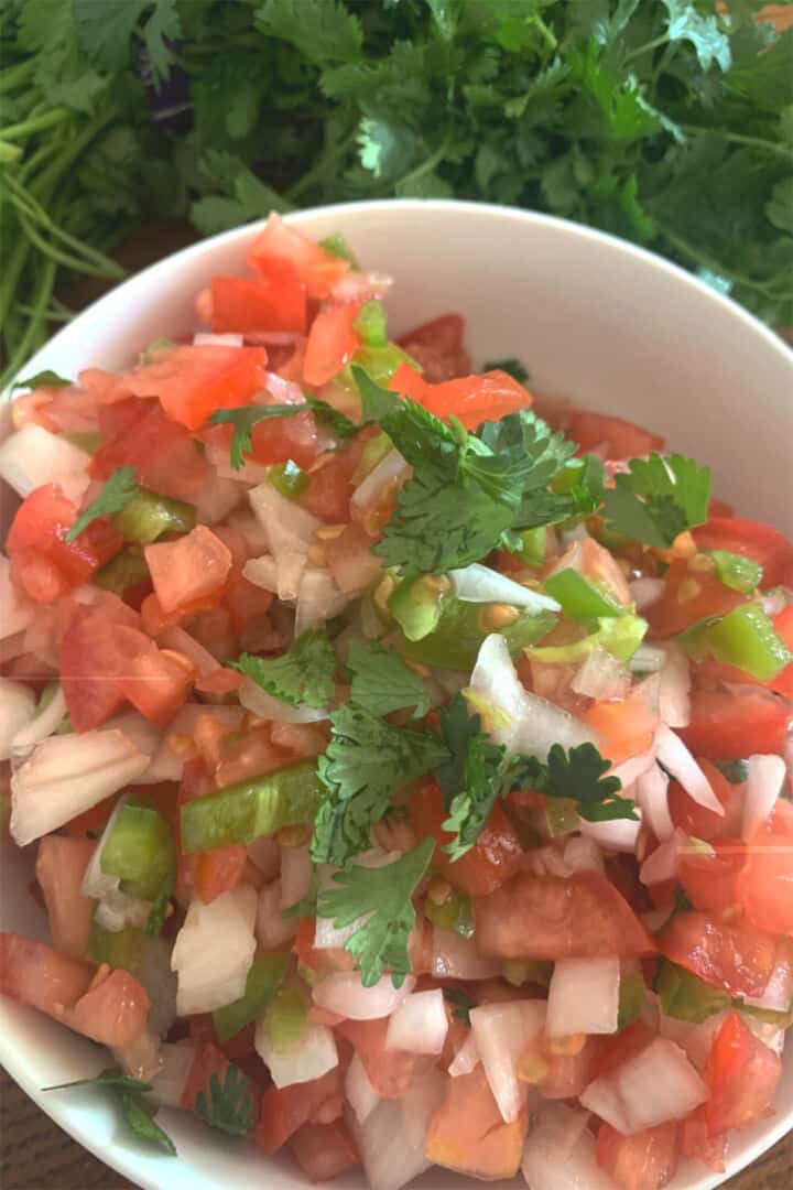 Fresh pico de gallo mixed in a bowl with tomatoes, onion, cilantro, and jalapeno.