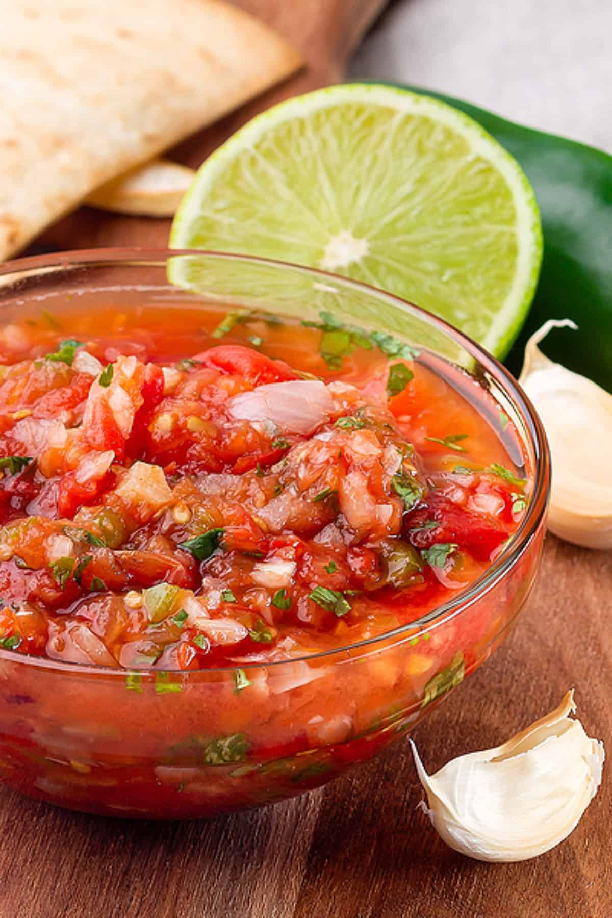 Pico de gallo served with tortilla chips on wooden board.