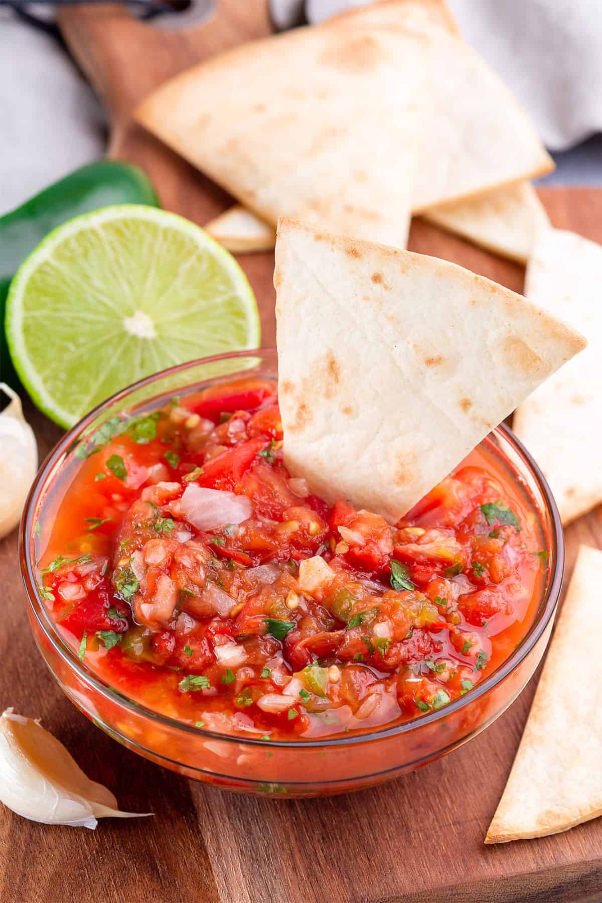 Fresh pico de gallo in a glass bowl with tomatoes, onion, cilantro, lime, and tortilla chips.