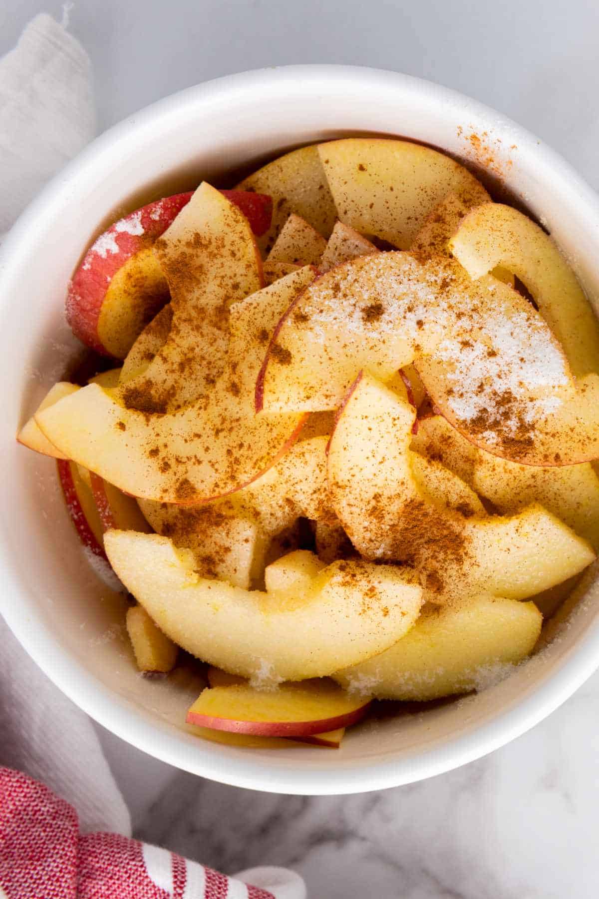 sliced apples in a bowl with sugar and cinnamon.