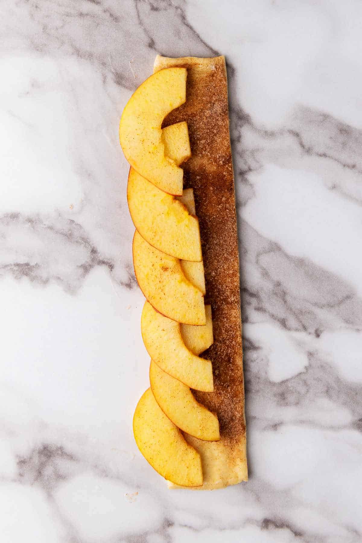 fruit slices layered on a strip of dough.