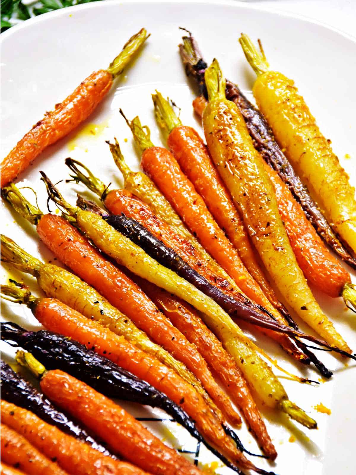 serving platter of roasted heirloom carrots garnished with herbs and olive oil