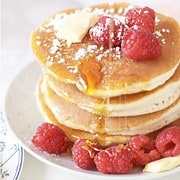 stack of pancakes with butter, fresh raspberries, and powdered sugar topping.