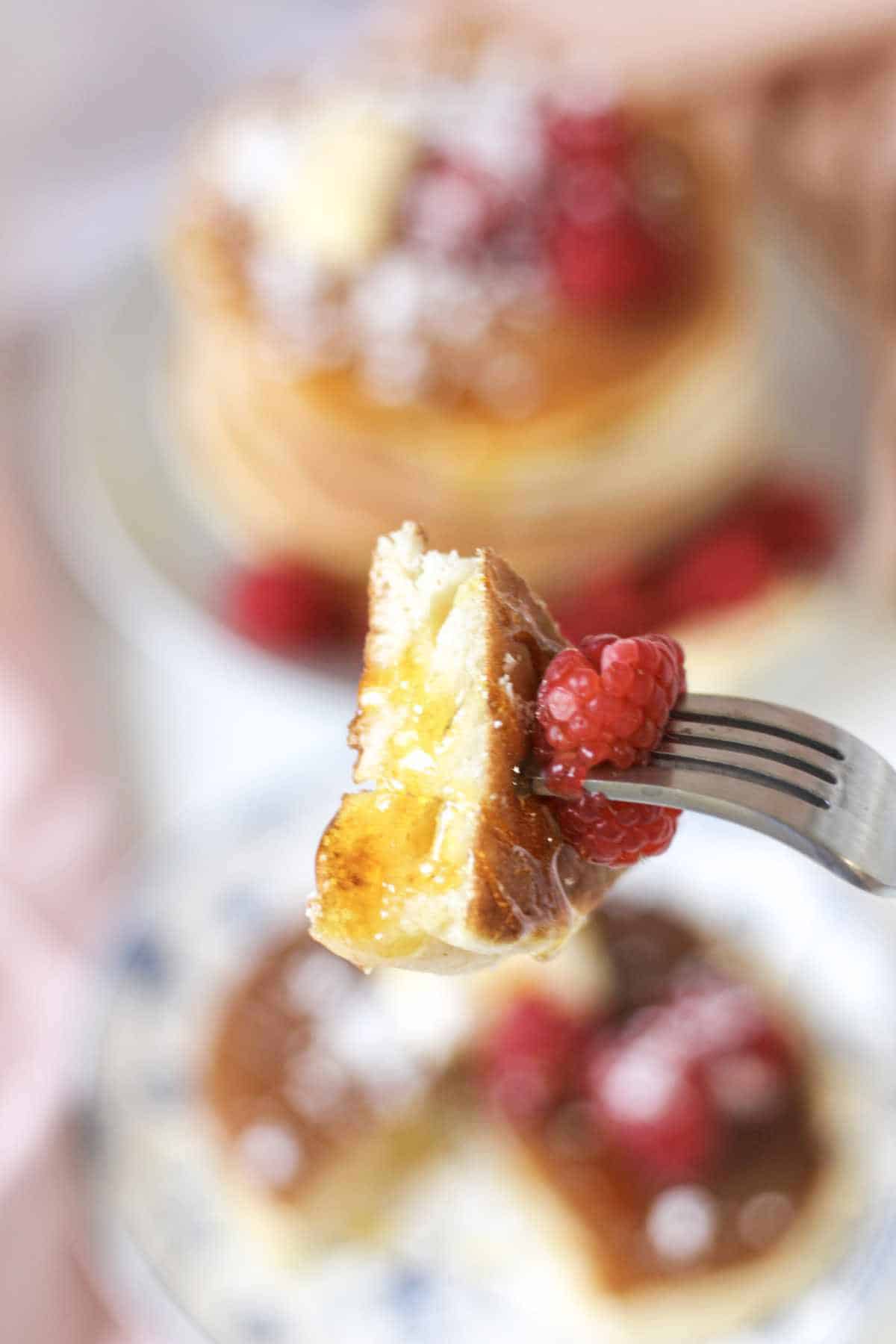 stack of pancakes with butter, fresh raspberries, and powdered sugar topping.