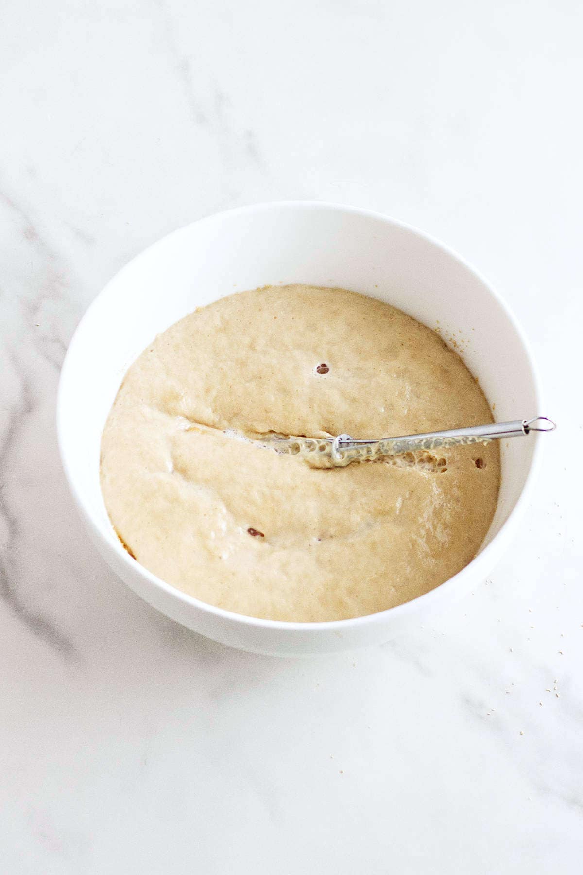 Foamy yeast mixture in a white bowl for Rosca de Reyes dough.