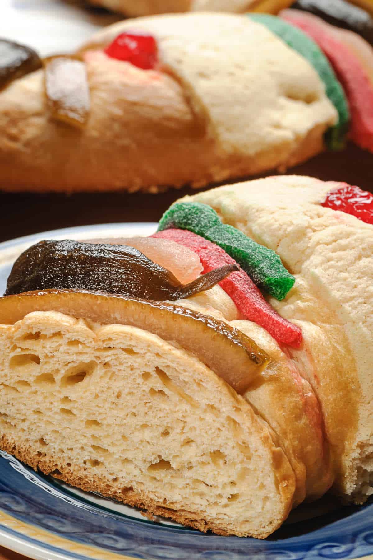 Slice of Rosca de Reyes filled with cinnamon sugar, raisins, and nuts and topped with candied fruit.
