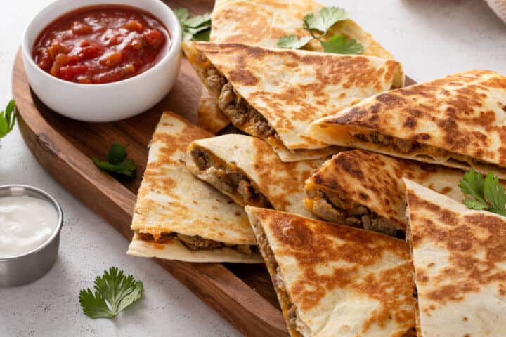 Steak quesadilla wedges on a white plate, partial striped napkin visible underneath.