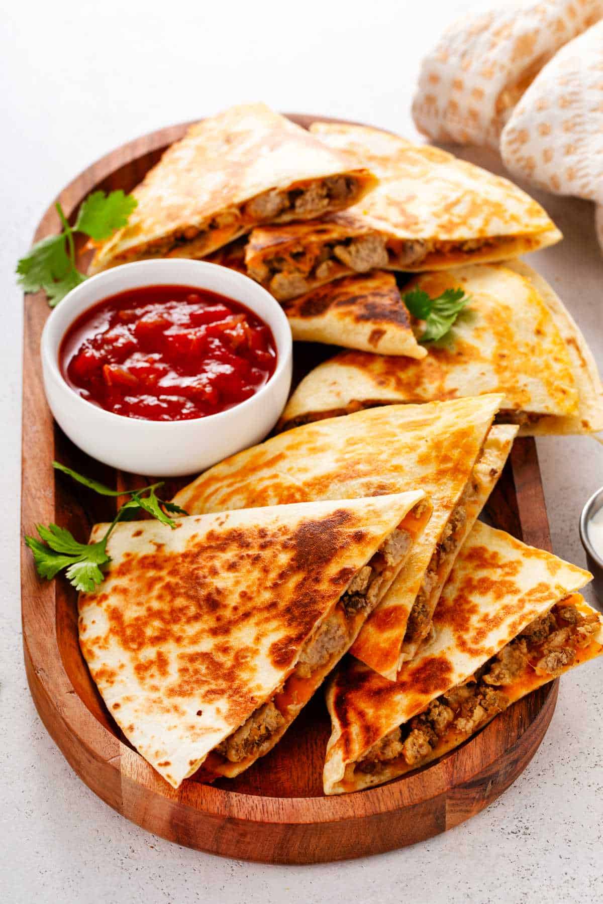 Sliced steak quesadilla filled with melted cheese and served with sour cream.