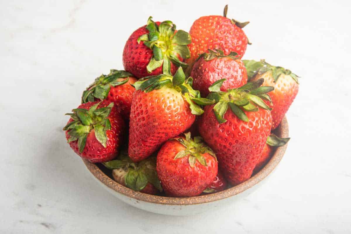 bowl of fresh strawberries on white marble.