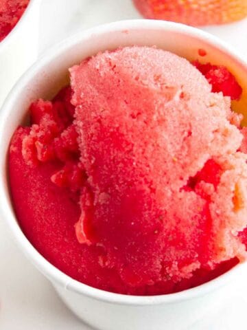 Strawberry sorbet in ice cream storage tubs.