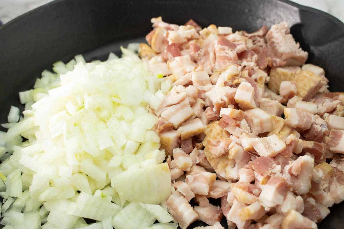 bacon and onions in a black cast iron skillet.
