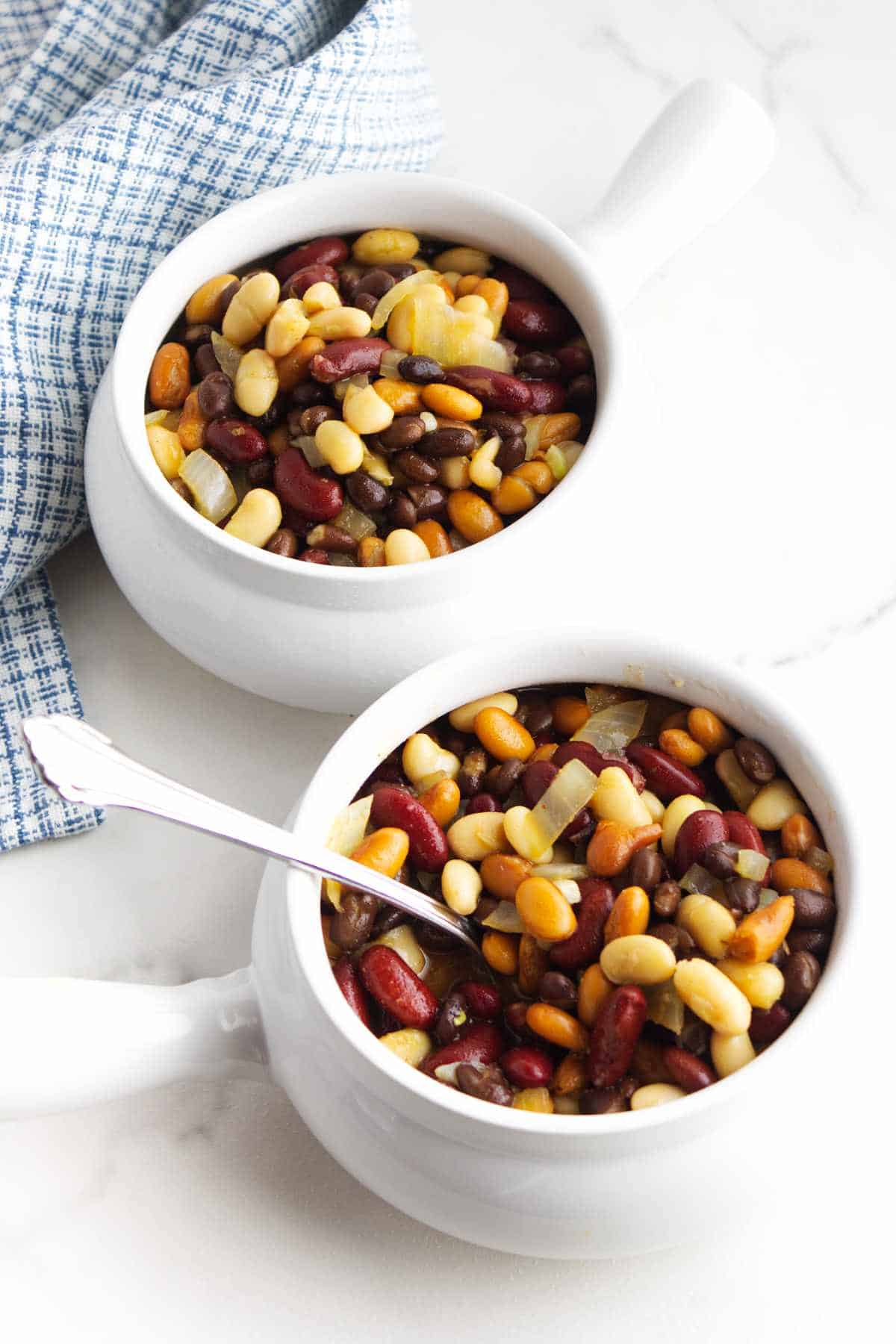 White handled soup bowls full of Texas Cowboy beans on a white backgroundPerfect for Crocktober. 