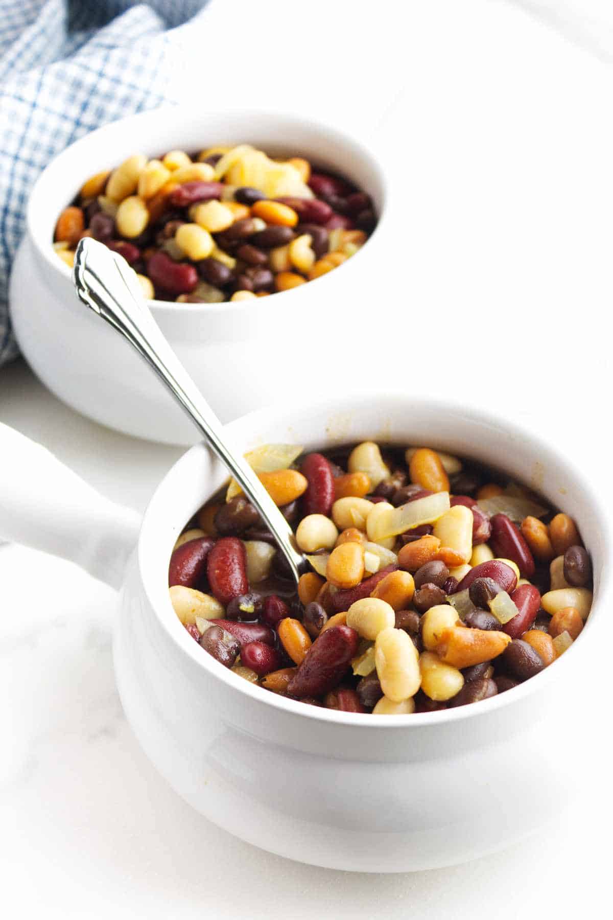 White handled soup bowls full of Texas Cowboy beans on a white background.
