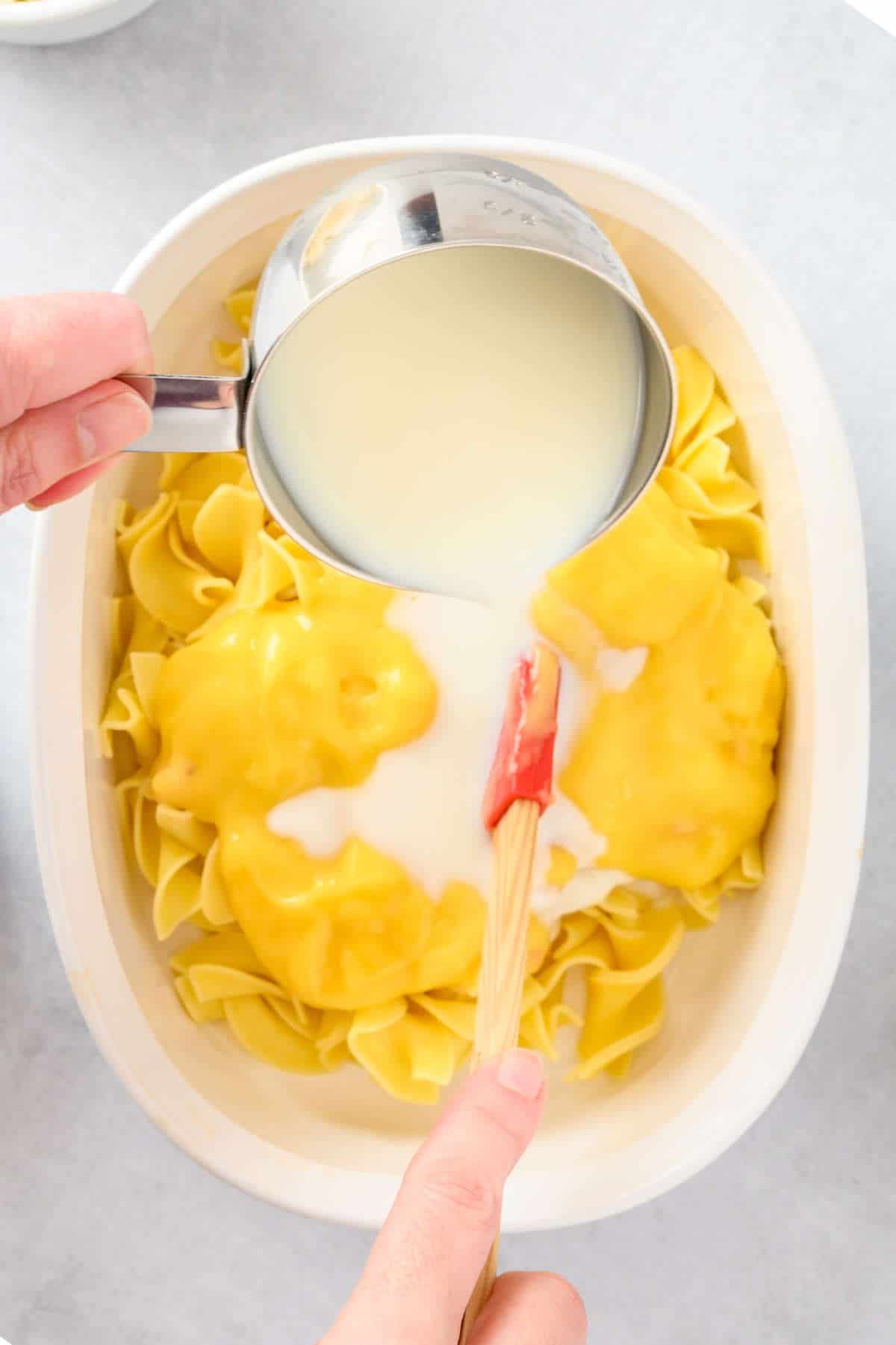 adding cream of mushroom soup, cottage cheese, and milk to the egg noodles.