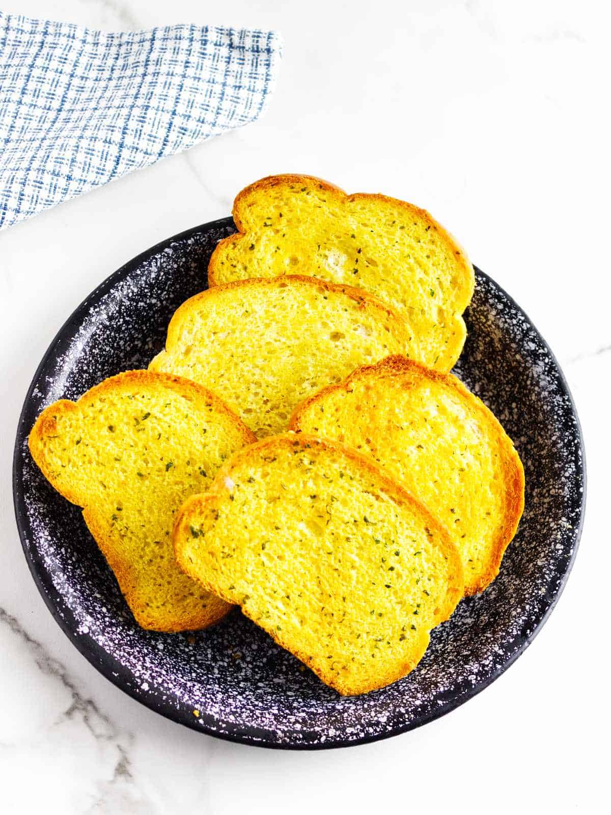 slices of toasted french bread on a blue speckled platter.