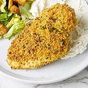 Panko crusted chicken breast on a serving plate with mashed potatoes and salad.