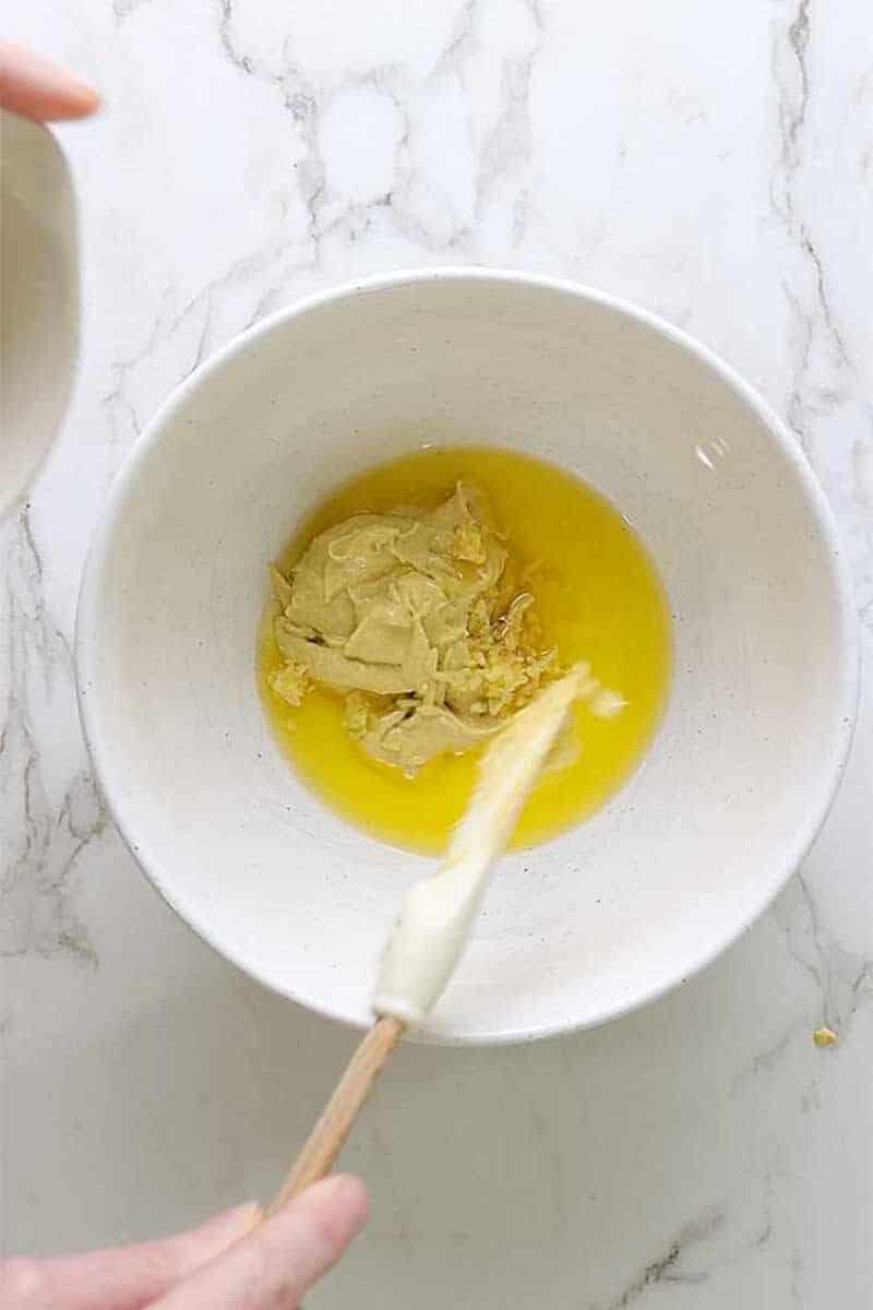 Mustard added to beaten egg in a bowl.