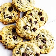 Bakery style chocolate chip cookies on a white marble background.