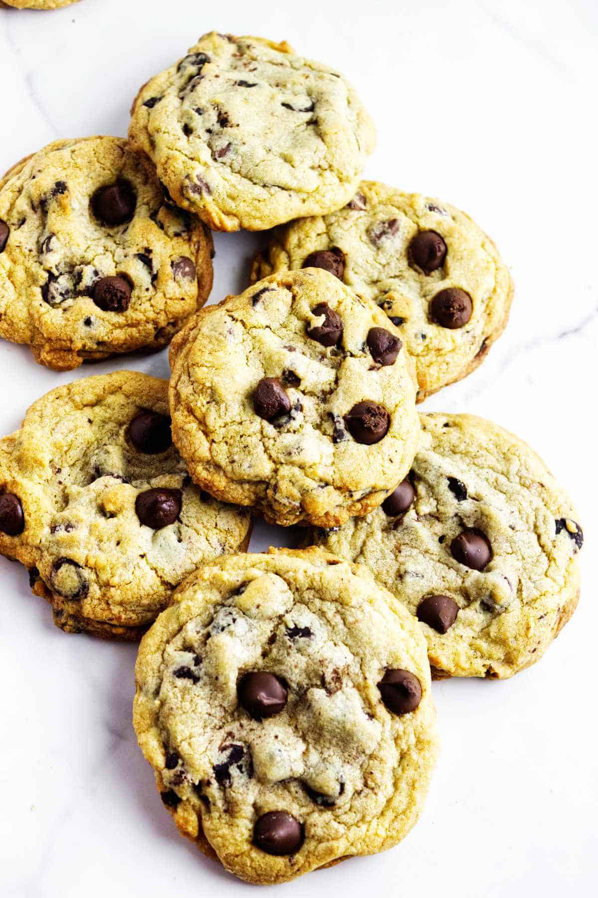 Bakery style chocolate chip cookies on a white marble background.
