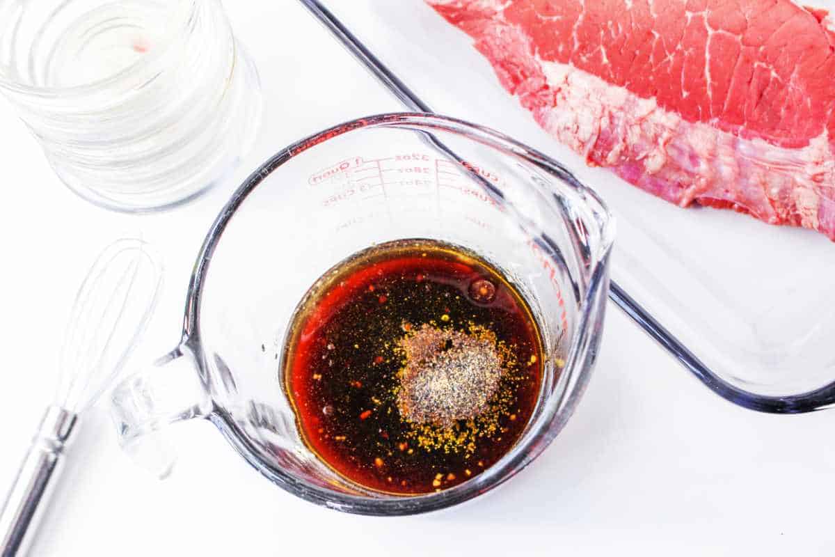 marinade in a glass measuring cup and beef in a glass baking dish.