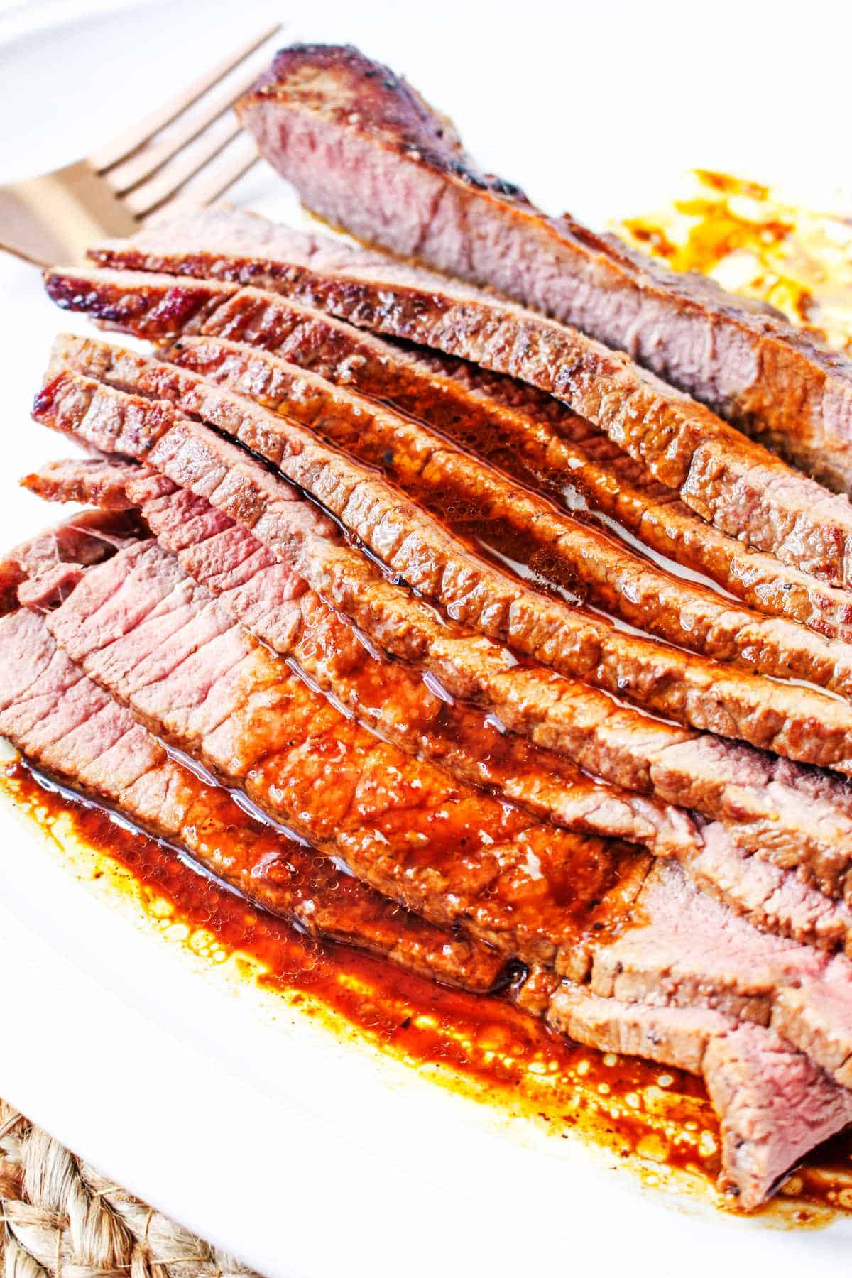 thinly sliced beef flank steak on a white platter.