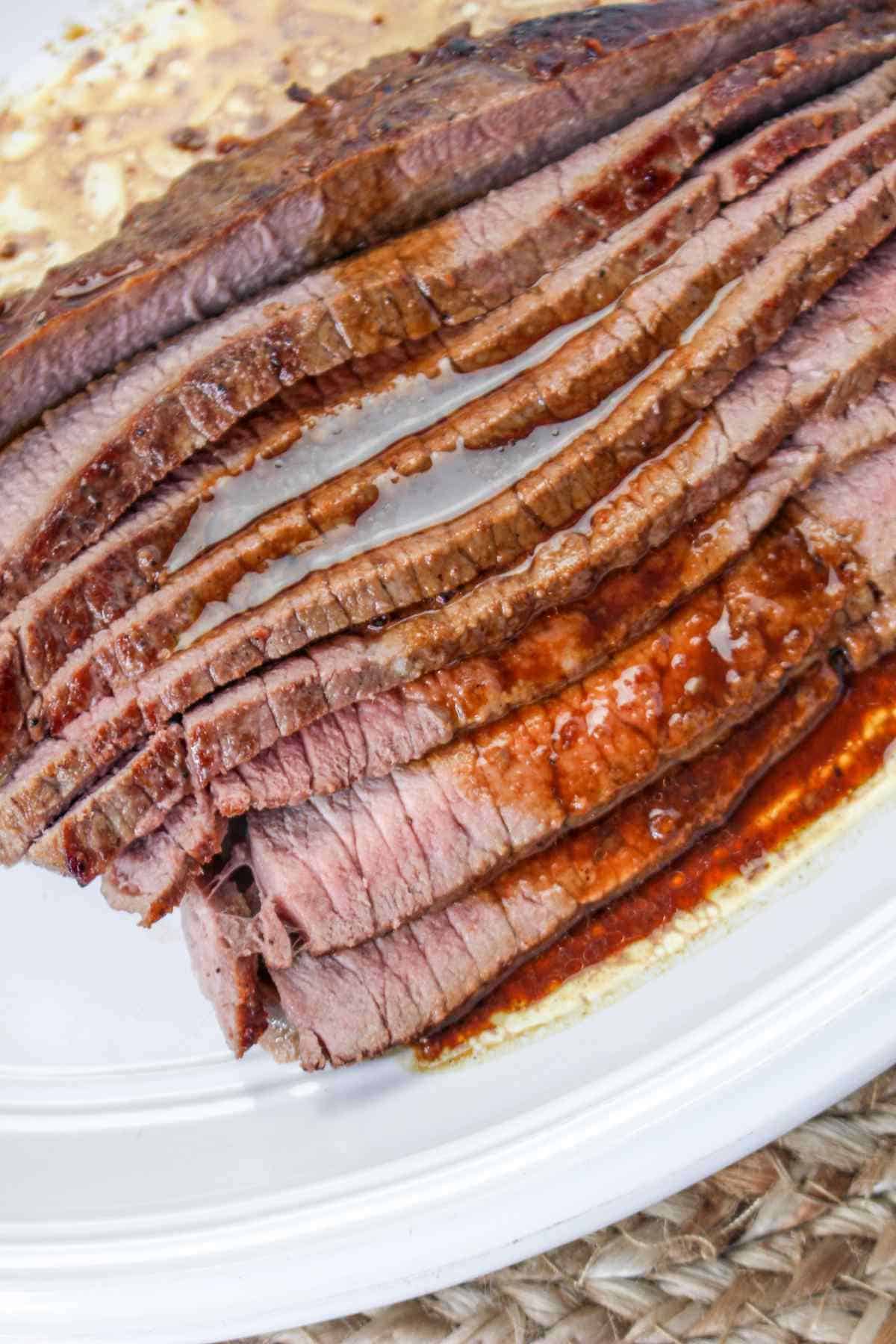 thinly sliced beef flank or skirt steak on a white platter.
